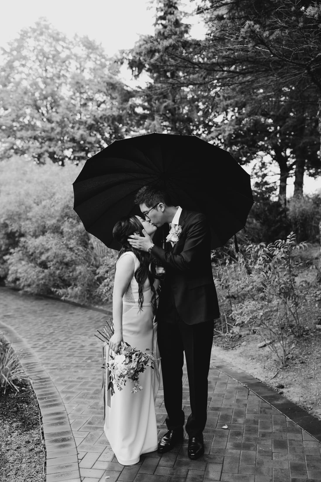 black and white bride and groom kissing in the rain arlington estate wedding eightyfifth street photography