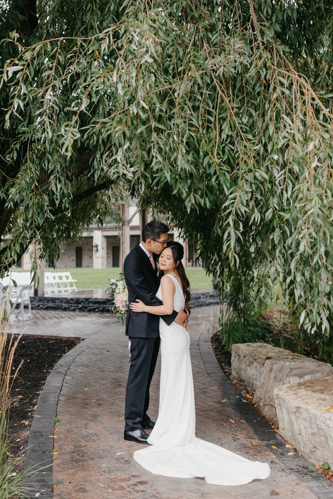 groom kissing bride under willow tree arlington estate wedding eightyfifth street photography